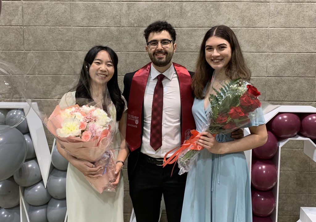 Elise Wan, David Mikhail, and Maya Verma pose with flowers in front of balloons spelling 'Mac'