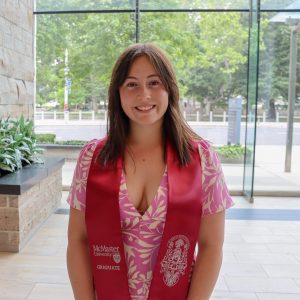 Graduate smiling in camera wearing a "Graduate" sash.
