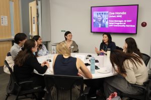 group of students sitting around a roundtable talking with an alumni facilitator.