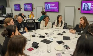 group of students sitting around a roundtable talking with an alumni facilitator.