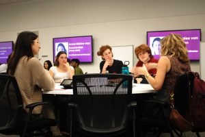 group of students sitting around a roundtable talking with an alumni facilitator.